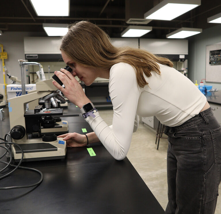 student looking through microscope in science lab