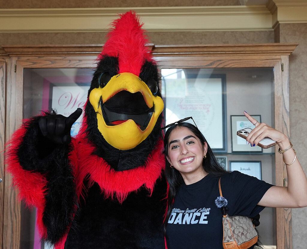 student posing with cardinal mascot