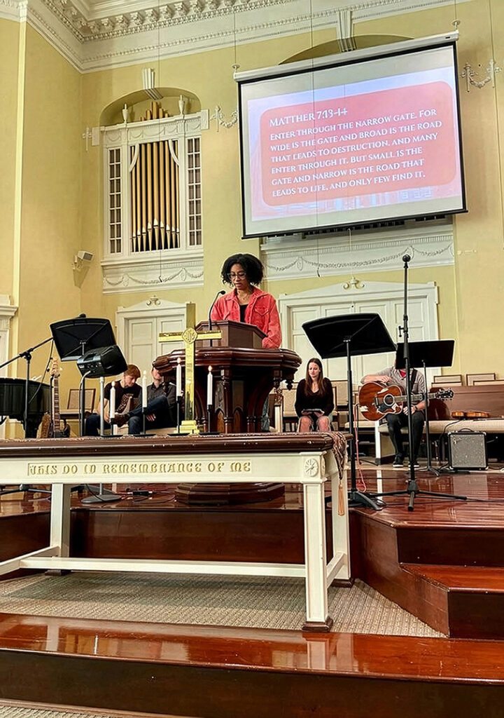 student at lectern at front of church reading Bible verse