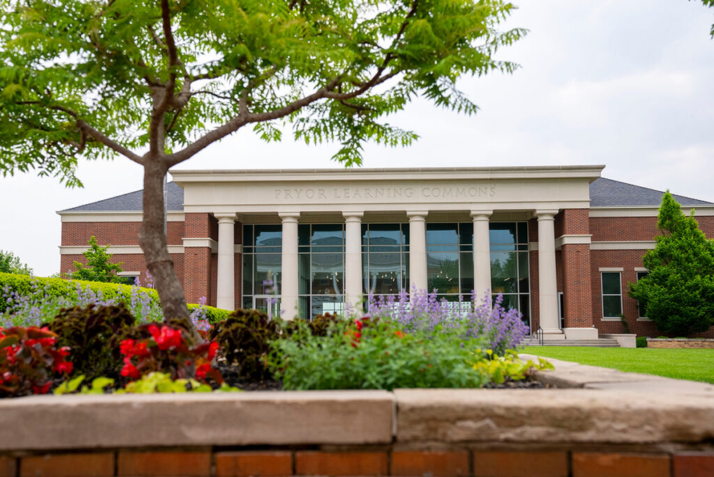 blooming flowers with Pryor Learning Commons in background