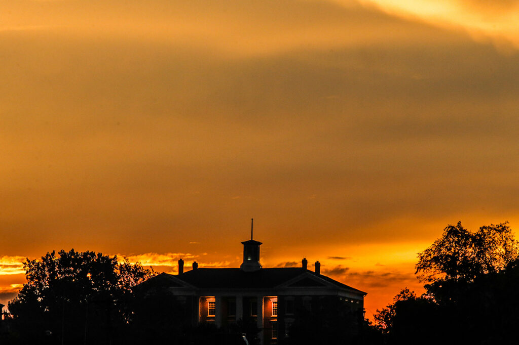 silhouette of Jewell Hall with yellow sky sunrise