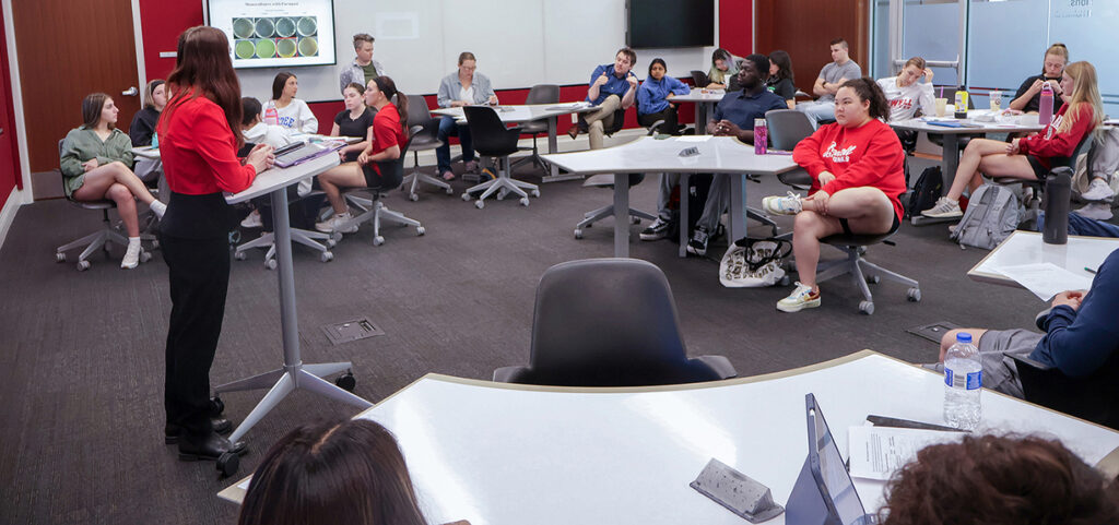 student presenter pointing at a slide on a projection screen